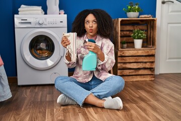 Canvas Print - Young african american woman cleaning shoes at laundry room making fish face with mouth and squinting eyes, crazy and comical.