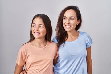 Canvas Print - Young mother and daughter standing over white background looking away to side with smile on face, natural expression. laughing confident.