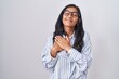 © Krakenimages.com - Young hispanic woman wearing glasses smiling with hands on chest with closed eyes and grateful gesture on face. health concept.