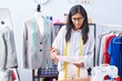 © Krakenimages.com - Young beautiful hispanic woman tailor smiling confident looking clothing design at clothing factory
