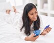 © Krakenimages.com - Young beautiful hispanic woman using laptop and credit card sitting on bed at bedroom