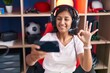 © Krakenimages.com - Young hispanic woman playing video games with smartphone doing ok sign with fingers, smiling friendly gesturing excellent symbol