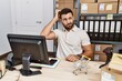 © Krakenimages.com - Handsome hispanic man working at small business commerce confuse and wondering about question. uncertain with doubt, thinking with hand on head. pensive concept.