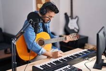 Young Hispanic Man Singing Song Playing Classical Guitar At Music Studio