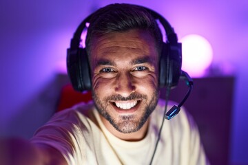 Canvas Print - Young hispanic man streamer smiling confident make selfie by camera at gaming room