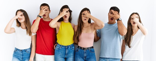 Canvas Print - Group of people wearing casual clothes standing over isolated background peeking in shock covering face and eyes with hand, looking through fingers with embarrassed expression.