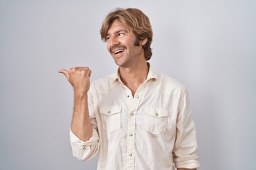 Poster - Middle age man standing over isolated background smiling with happy face looking and pointing to the side with thumb up.