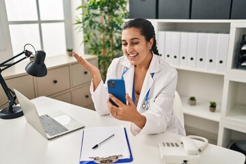 Poster - Young doctor hispanic woman doing video call celebrating achievement with happy smile and winner expression with raised hand