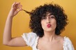 canvas print picture - Young brunette woman with curly hair holding curl looking at the camera blowing a kiss being lovely and sexy. love expression.