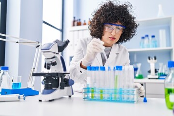 Wall Mural - Young middle east woman scientist pouring liquid on test tubes at laboratory