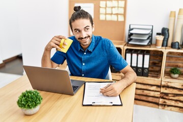 Wall Mural - Handsome hispanic man working and drinking a coffee at the office