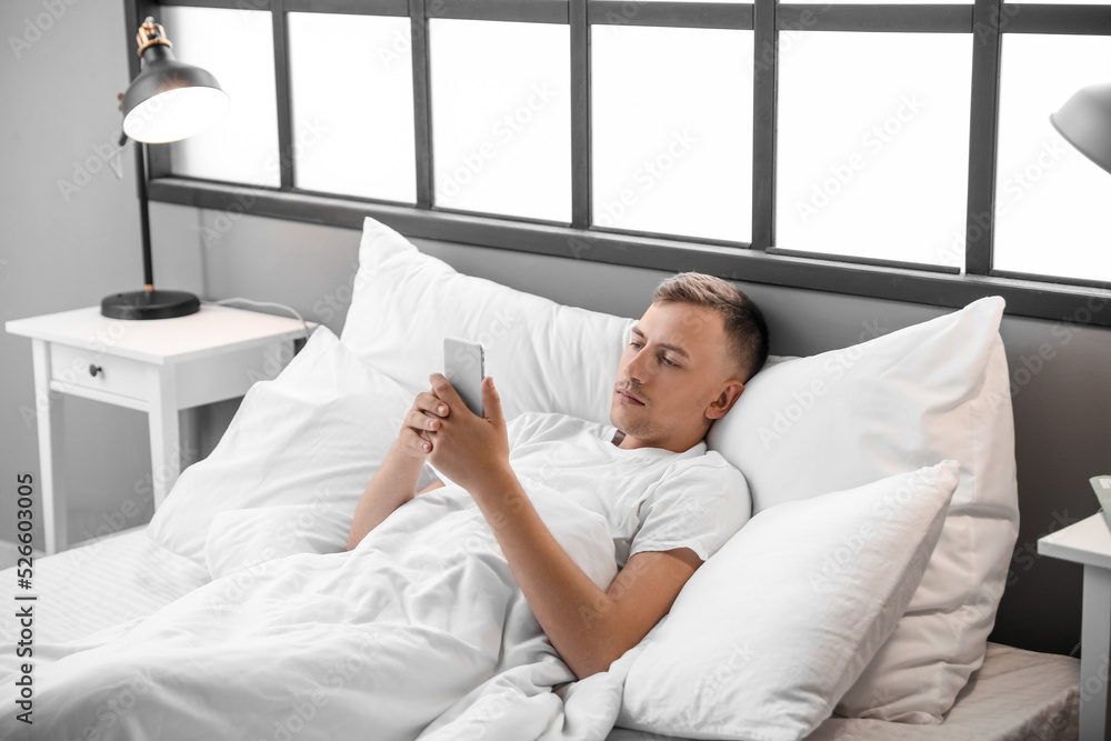 Young man using mobile phone at home in morning