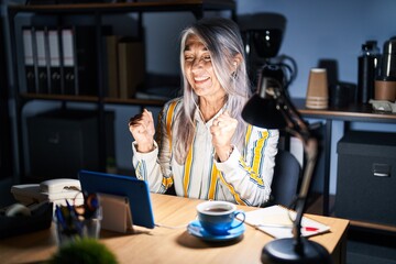 Poster - Middle age woman with grey hair working at the office at night excited for success with arms raised and eyes closed celebrating victory smiling. winner concept.