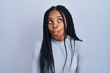 Poster - African american woman standing over blue background making fish face with lips, crazy and comical gesture. funny expression.