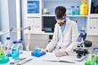 © Krakenimages.com - Young hispanic man scientist writing on notebook measuring liquid at laboratory