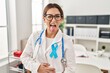 Young brunette doctor woman wearing stethoscope at the clinic sticking tongue out happy with funny expression. emotion concept.