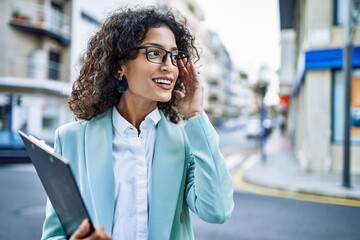 Wall Mural - Young hispanic business woman wearing professional look smiling confident at the city