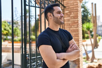 Wall Mural - Young hispanic man smiling confident standing with arms crossed gesture at street