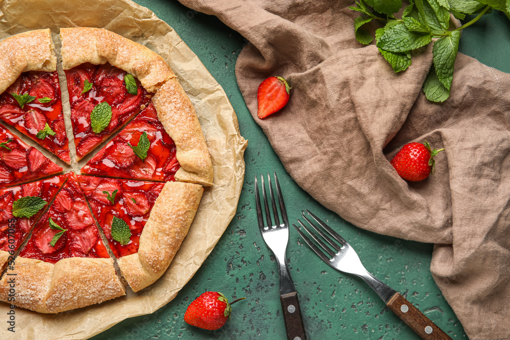 Composition with tasty strawberry galette and forks on green background
