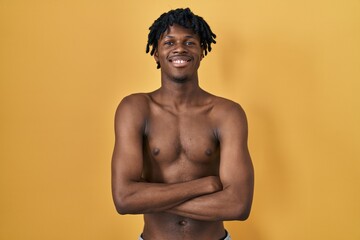 Poster - Young african man with dreadlocks standing shirtless happy face smiling with crossed arms looking at the camera. positive person.