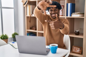 Sticker - Young african man with dreadlocks working using computer laptop smiling making frame with hands and fingers with happy face. creativity and photography concept.