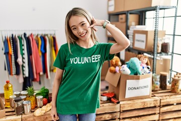 Sticker - Asian young woman wearing volunteer t shirt at donations stand smiling doing phone gesture with hand and fingers like talking on the telephone. communicating concepts.