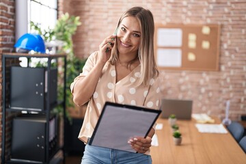 Canvas Print - Young caucasian woman business worker talking on smartphone reading document at office