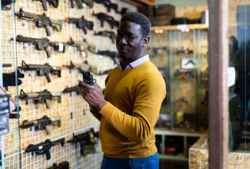 Wall Mural - Portrait of confident african american man in gun shop showing rifle