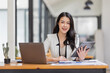 © David - Female Business Asian working on documents on tablet laptop in the workplace, Young asian woman sitting at table doing planning financial report, business plan investment, finance analysis concept.