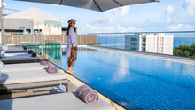 Asia Women With A Hat At A Rooftop Swimming Pool At A Luxury Hotel,Rooftop Swimming Pool At A Luxury Hotel, Luxury Pool On A Rooftop Looking Out Over Ocean