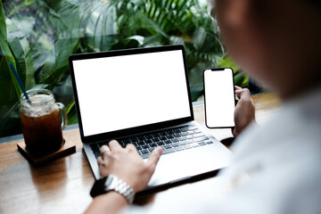 mockup image computer,cell phone blank screen for hand typing text,using laptop contact business searching information in workplace on desk at office.design creative work space on wooden desk