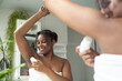 © gpointstudio - African-American woman feeling fresh while applying roll on antiperspirant