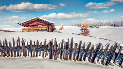 Wall Mural - Untouched winter landscape. Wooden chalet on the snowy hill of Alpe di Siusi village. Panoramic winter view of Dolomite Alps. Bright landscape of ski resort, Ityaly. Traveling concept background.