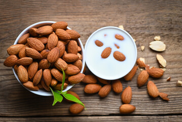 Canvas Print - Almond milk and Almonds nuts on on wooden background, Delicious sweet almonds on the table, roasted almond nut for healthy food and snack - top view