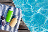Fototapeta Kawa jest smaczna - Cosmetic bottles and sunglasses near swimming pool