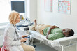 © Westend61 - Doctor talking with patient lying on bed doing ultrasound in clinic