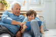 © Westend61 - Smiling boy sharing tablet PC with grandfather at home