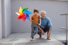 Smiling Boy With Multi Colored Pinwheel Toy By Grandfather At Corridor