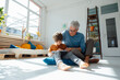 © Westend61 - Smiling grandson using tablet computer by grandfather in living room at home