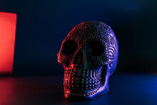 Black Human Skull Decorated With Golden Points Pattern In Neon Purple And Red Light On Dark Blue Background. Halloween Decor Concept. Selective Focus, Copy Space