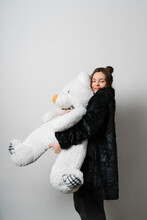Smiling Young Woman Embracing Teddy Bear In Studio