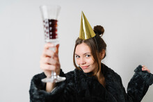 Young Woman With Wineglass Wearing Party Hat Against White Background