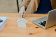 © SOMKID - Businesswoman holds a house model, Business home loan and insurance concept.