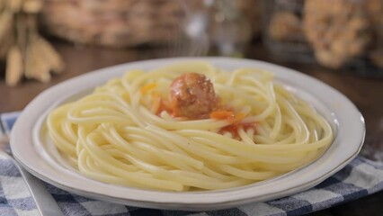 Wall Mural - plate of pasta with meatballs on a wooden table. Traditional meatballs with tomato bolognese sauce and herbs. baby food . High quality 4k footage. Hot steam from a dish