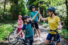 Young Family With Little Children Preapring For Bike Ride, Standing With Bicycles In Nature And High Fiving.