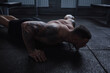 Strong muscular male athlete working out shirtless, doing push-ups