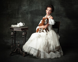 Wall Mural - Lady with dog. Vintage portrait of young elegant woman in image of medieval person in renaissance style dress isolated on dark background.