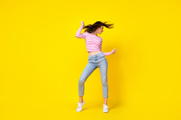 Wall Mural - Full size photo of pretty nice cute woman dressed striped shirt jeans white sneakers dancing have fun isolated on yellow color background