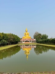 Sticker - Beautiful shot of a golden Buddha statue in front of a small lake