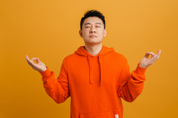 Wall Mural - Asian young man wearing hoodie gesturing and meditating